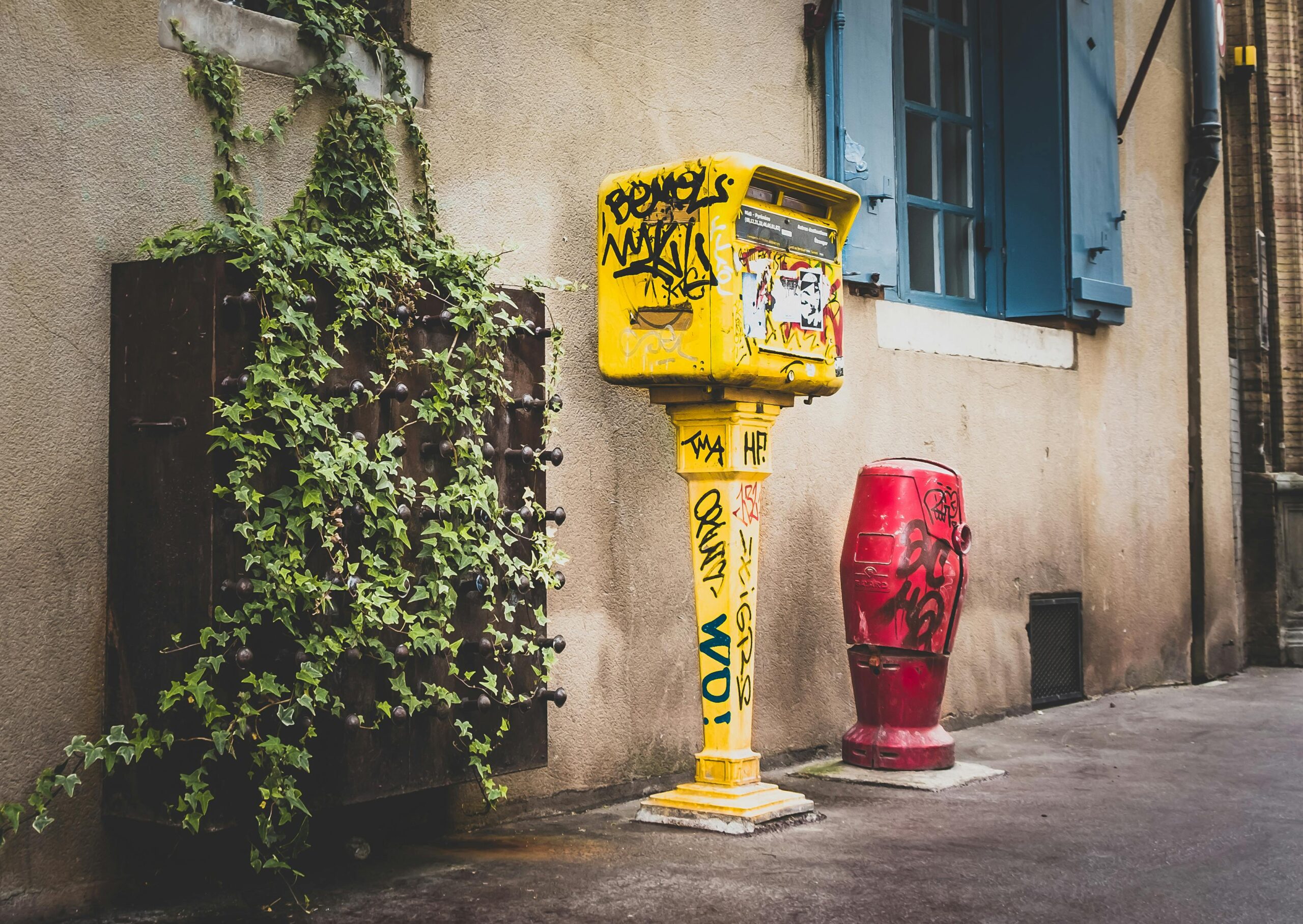 Explore vibrant urban art on graffiti-covered mailboxes in Toulouse, France alley.