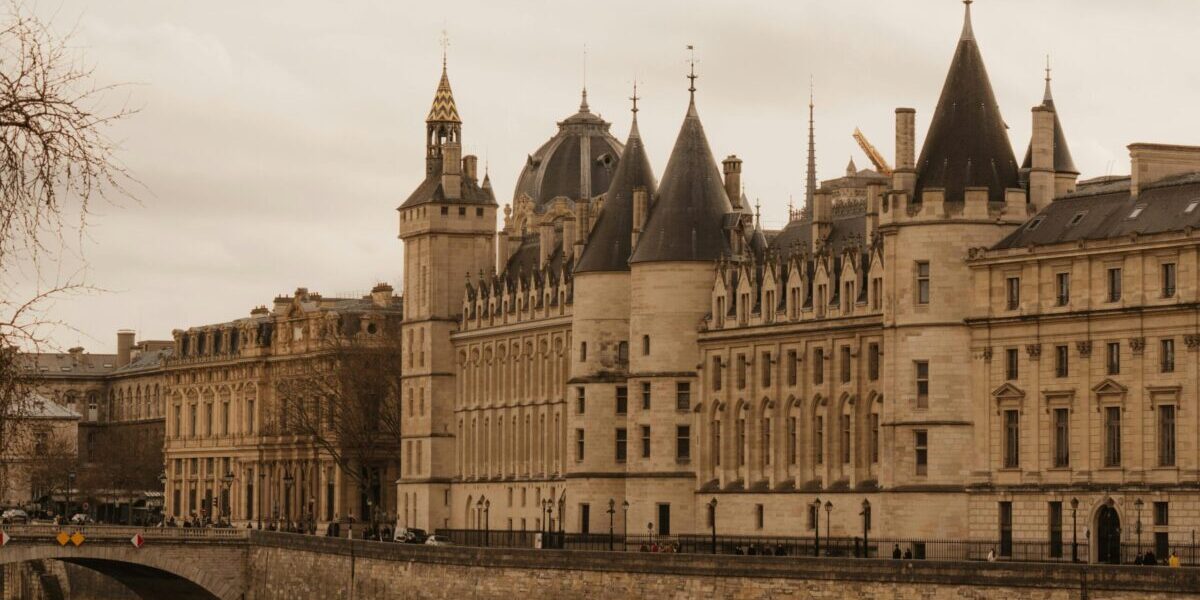 Capture of the historic Conciergerie in Paris along the Seine River showing its gothic architecture and riverside setting.