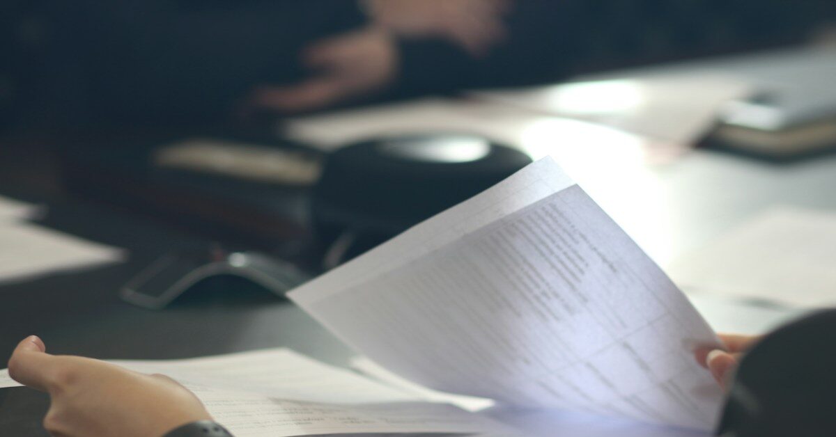 a woman sitting at a table reading a paper